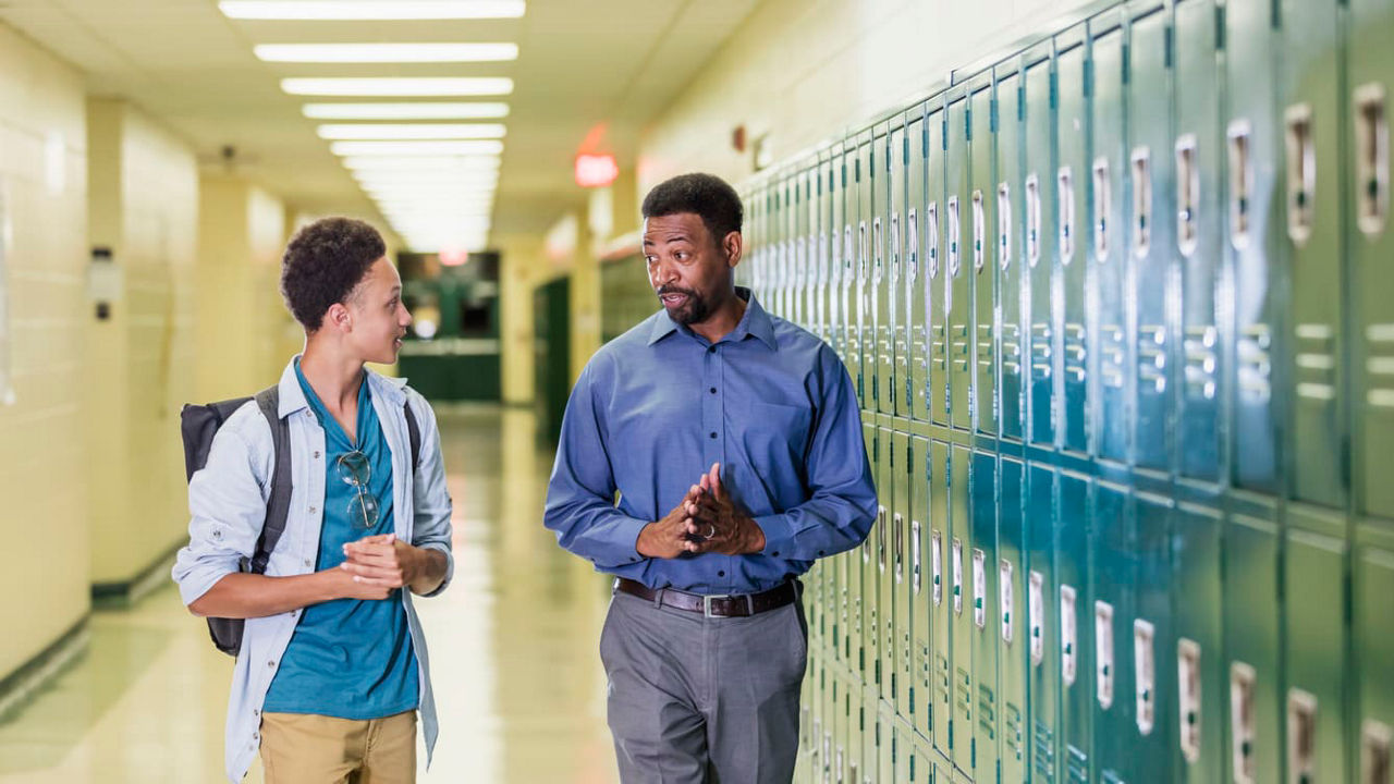 Two men talking in the hallway of a school.