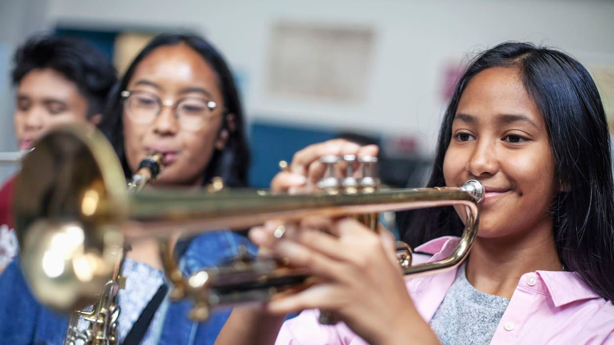 Two girls playing the trumpet in a classroom.