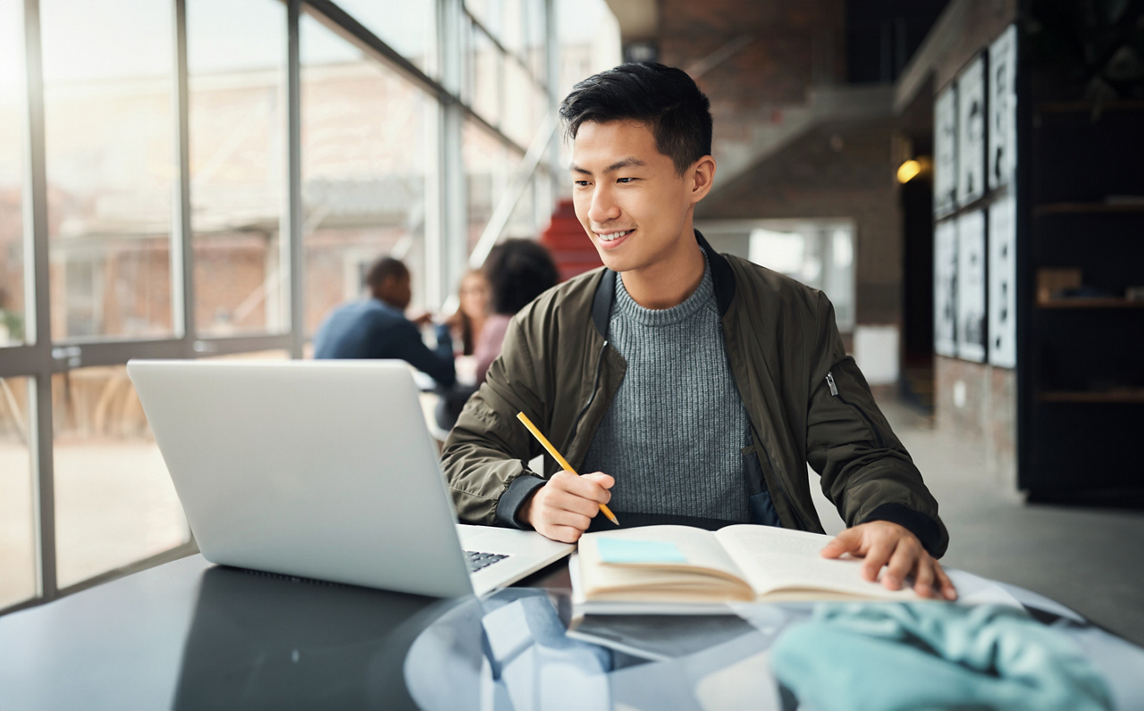 College student, asian man and studying on laptop at campus, research and education test, exam books and course project. Happy Japanese university student, knowledge and learning online technology