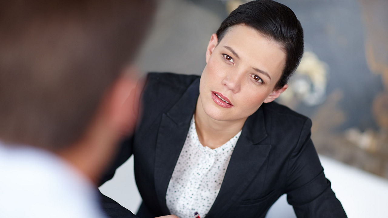 A woman is talking to a man in a business meeting.