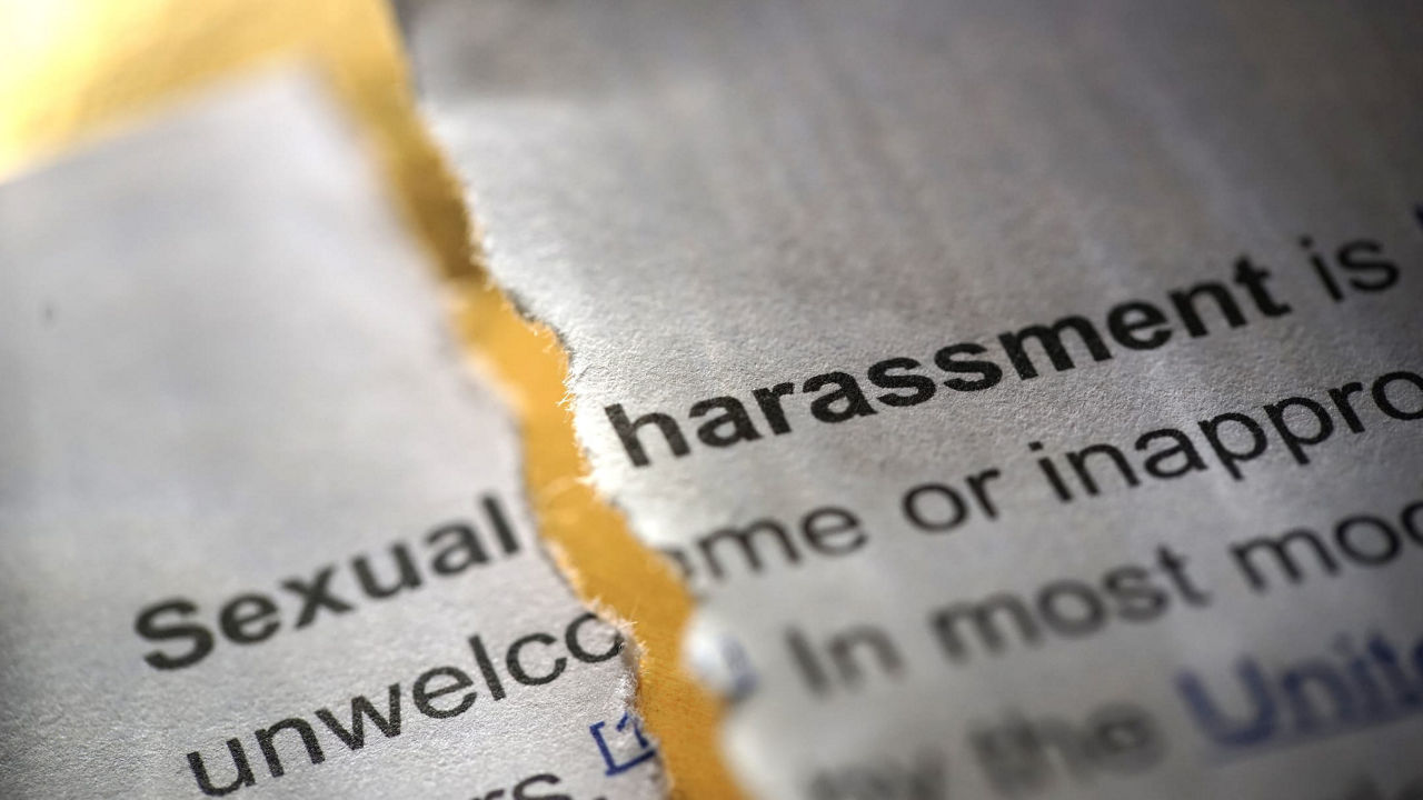 The word sexual harassment is torn out of a newspaper.