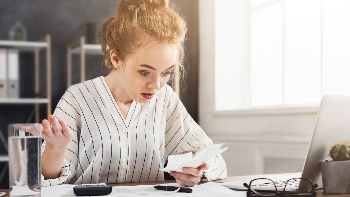 A woman sitting at a desk with papers and a laptop.