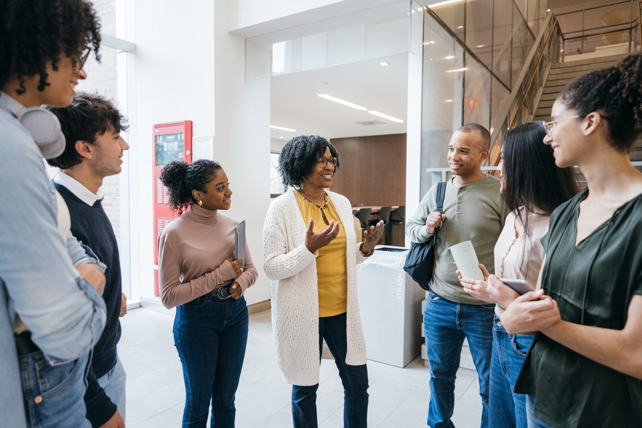 Teacher talks to students in modern University lobby