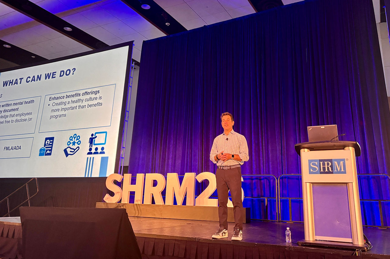 Michael Cohen faces the audience as he presents on stage at SHRM26.