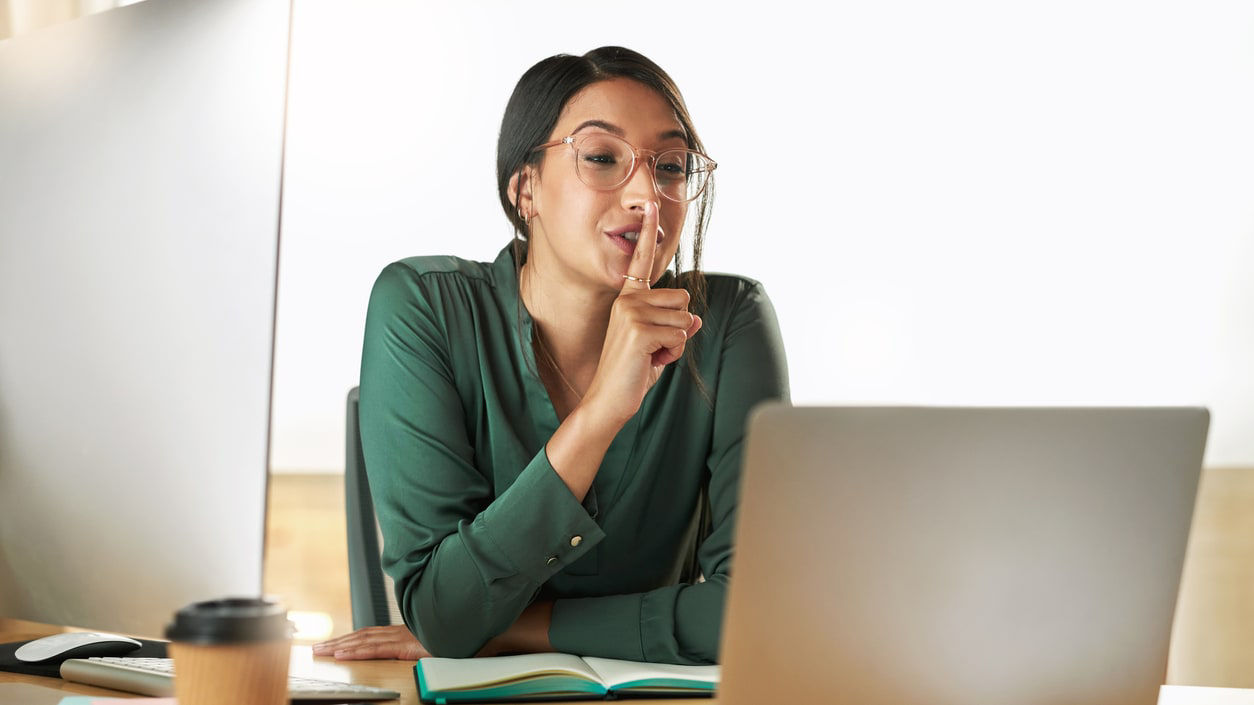 A woman is sitting at a desk with a laptop in front of her.