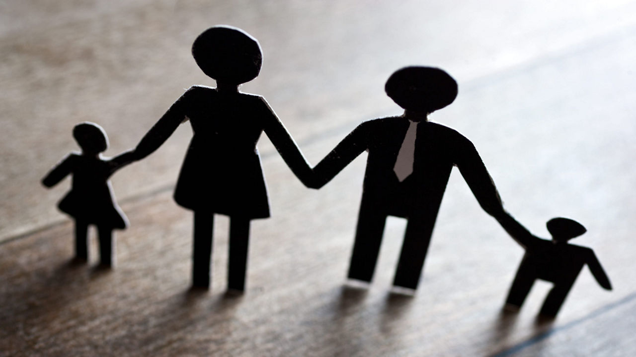 A black and white silhouette of a family holding hands.