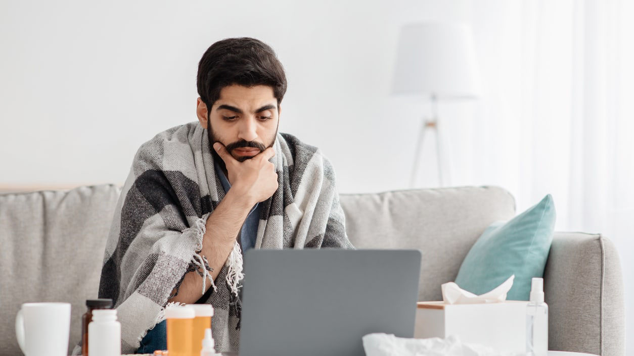 A man sitting on a couch with a laptop on his lap.
