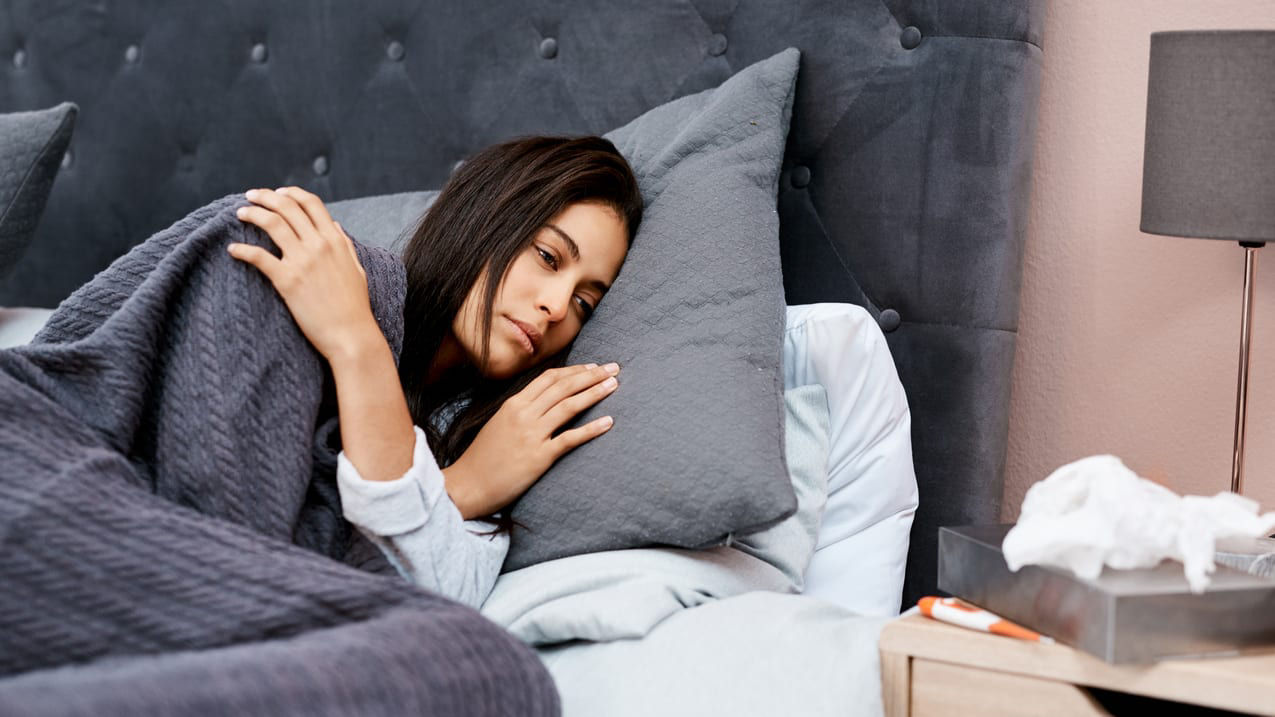A woman is sleeping in bed with a blanket on her head.