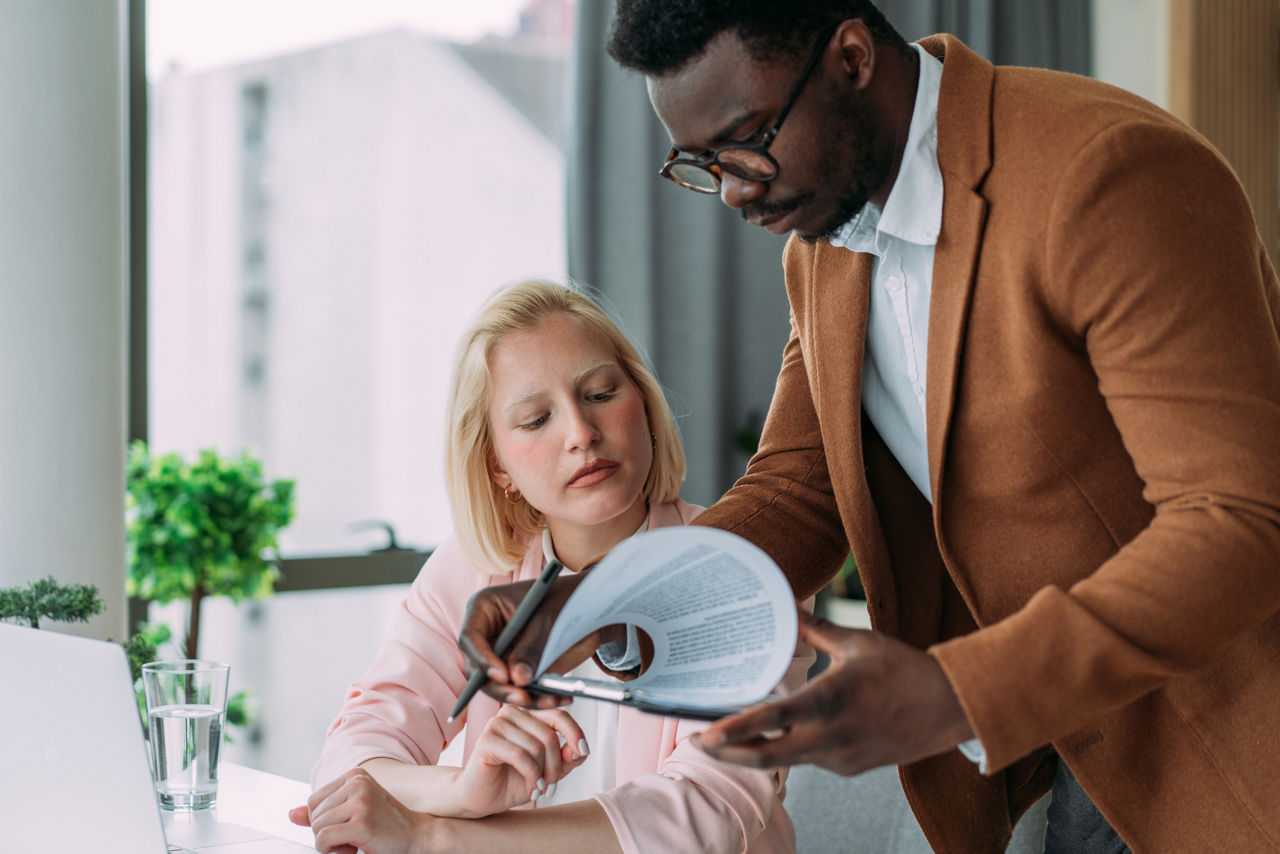 A worker about to sign a document in the presence of another worker.