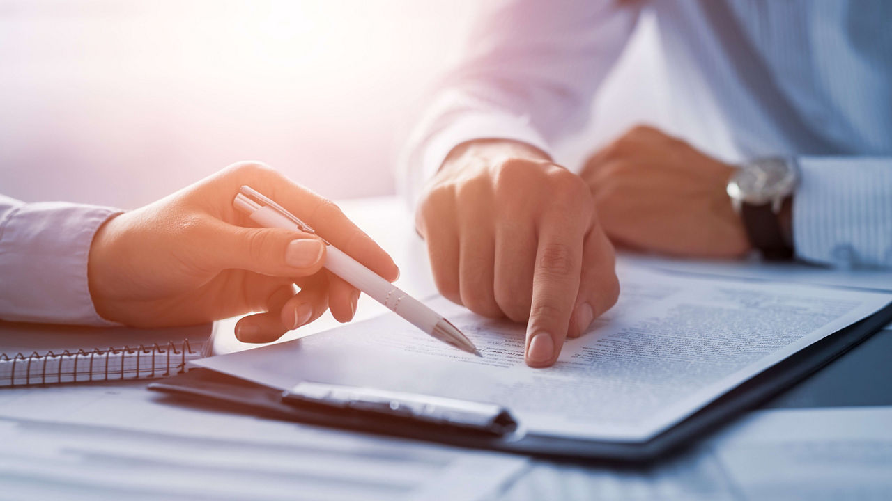 Two people signing a document at a desk.