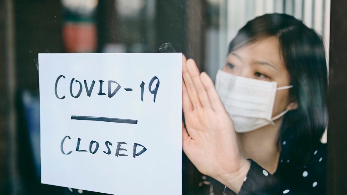 A woman holding a sign that says covid-19 closed.