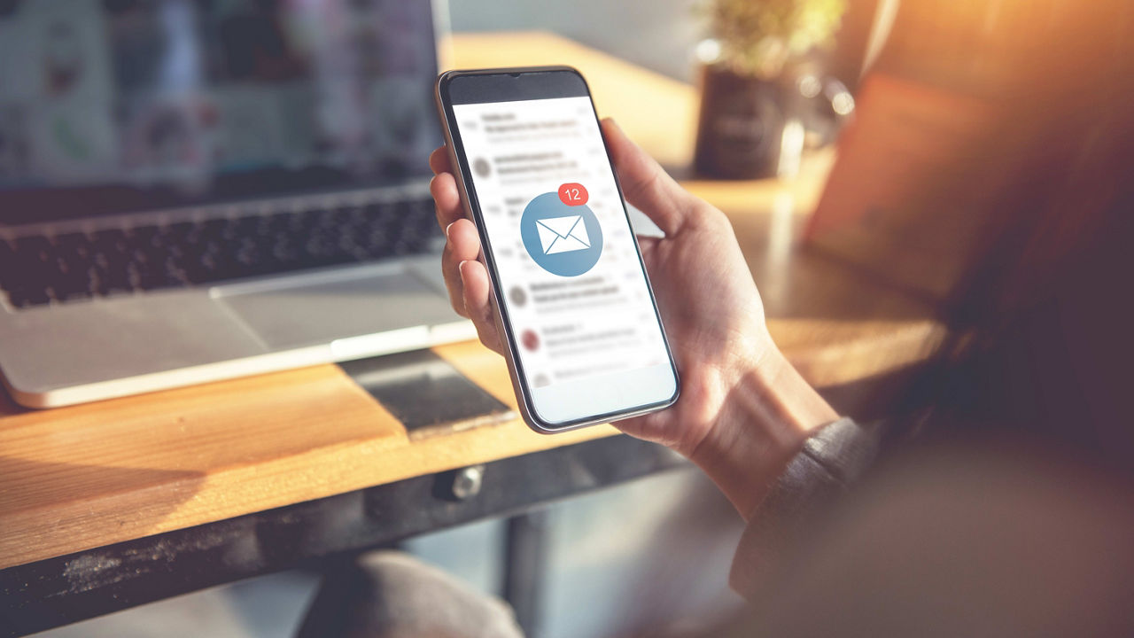 A woman is holding a phone with an email icon on it.