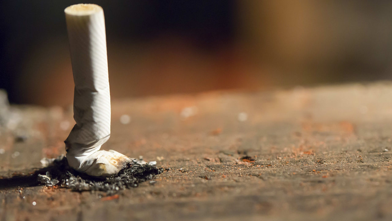 A cigarette is sitting on top of a wooden table.