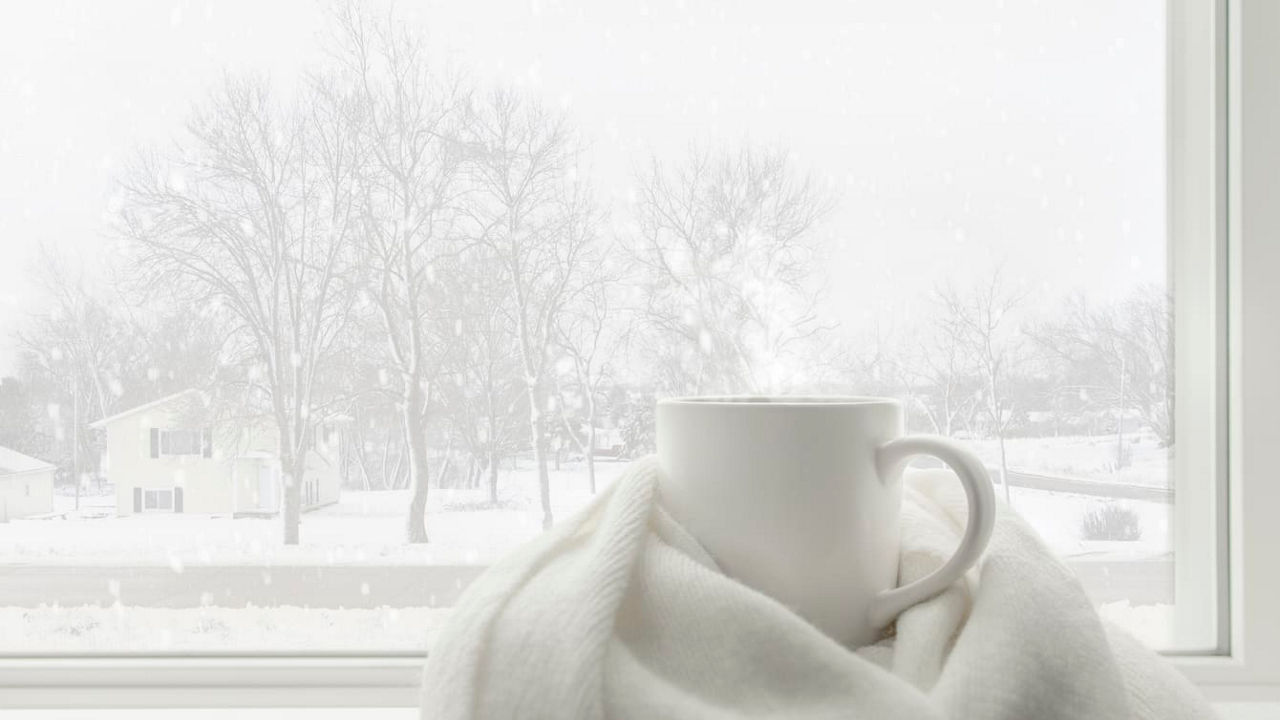 A cup of coffee sits on a window sill.