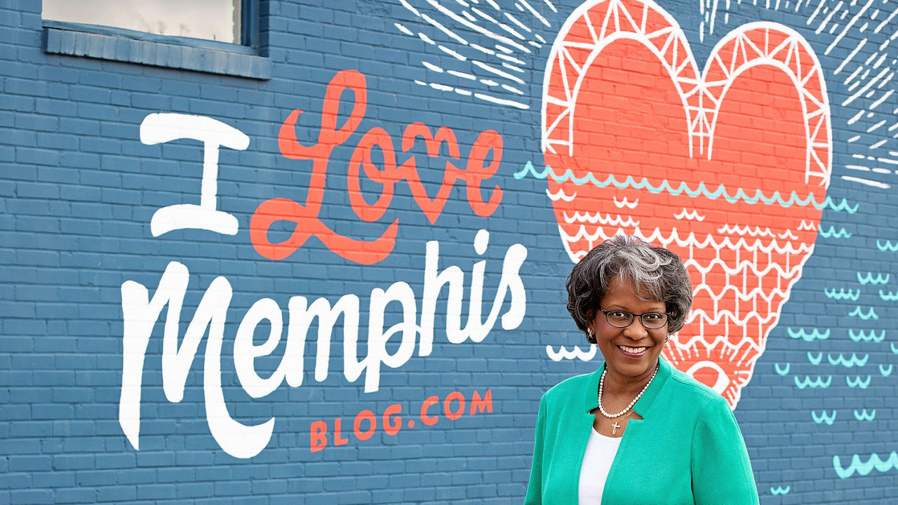 A woman standing in front of a mural that says i love memphis.