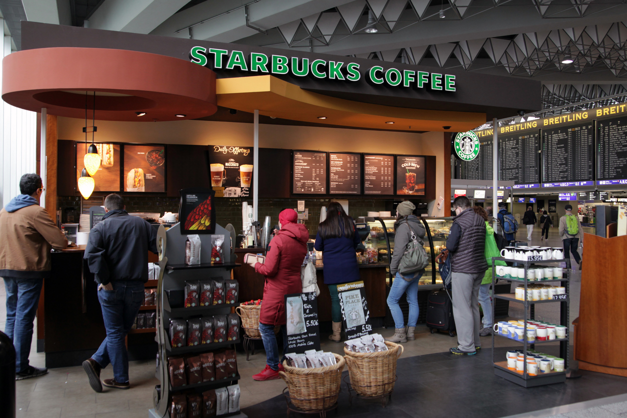 Frankfurt, Germany - April 27, 2016: Passengers waiting for their flight queing up on a Starbucks coffee and snack bar for a little drink or a piece of cake at Frankfurt Airport. Shot was taken on a day of strike at the airport with many flights cancelled or delayed, so the queue is longer than usual.