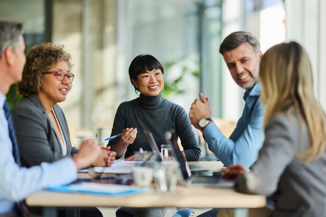 Group of happy multiracial entrepreneurs communicating during a meeting in the office. Focus is on Japanese woman.