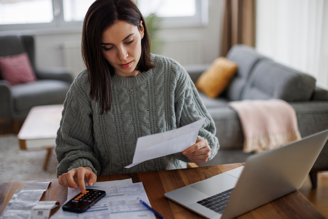 woman looking at a statement by a laptop