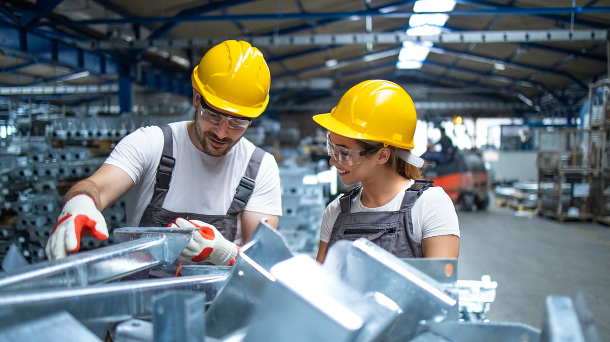 Two workers in hard hats working in a factory.