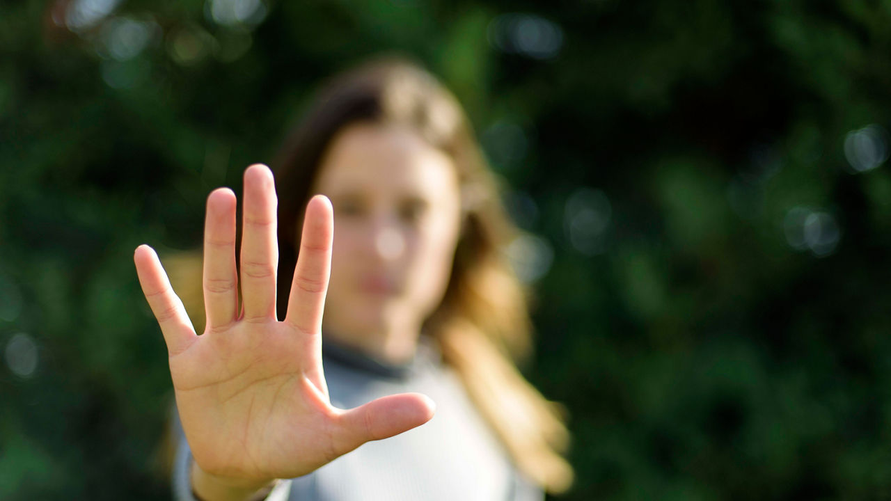 A woman is making a stop sign with her hand.