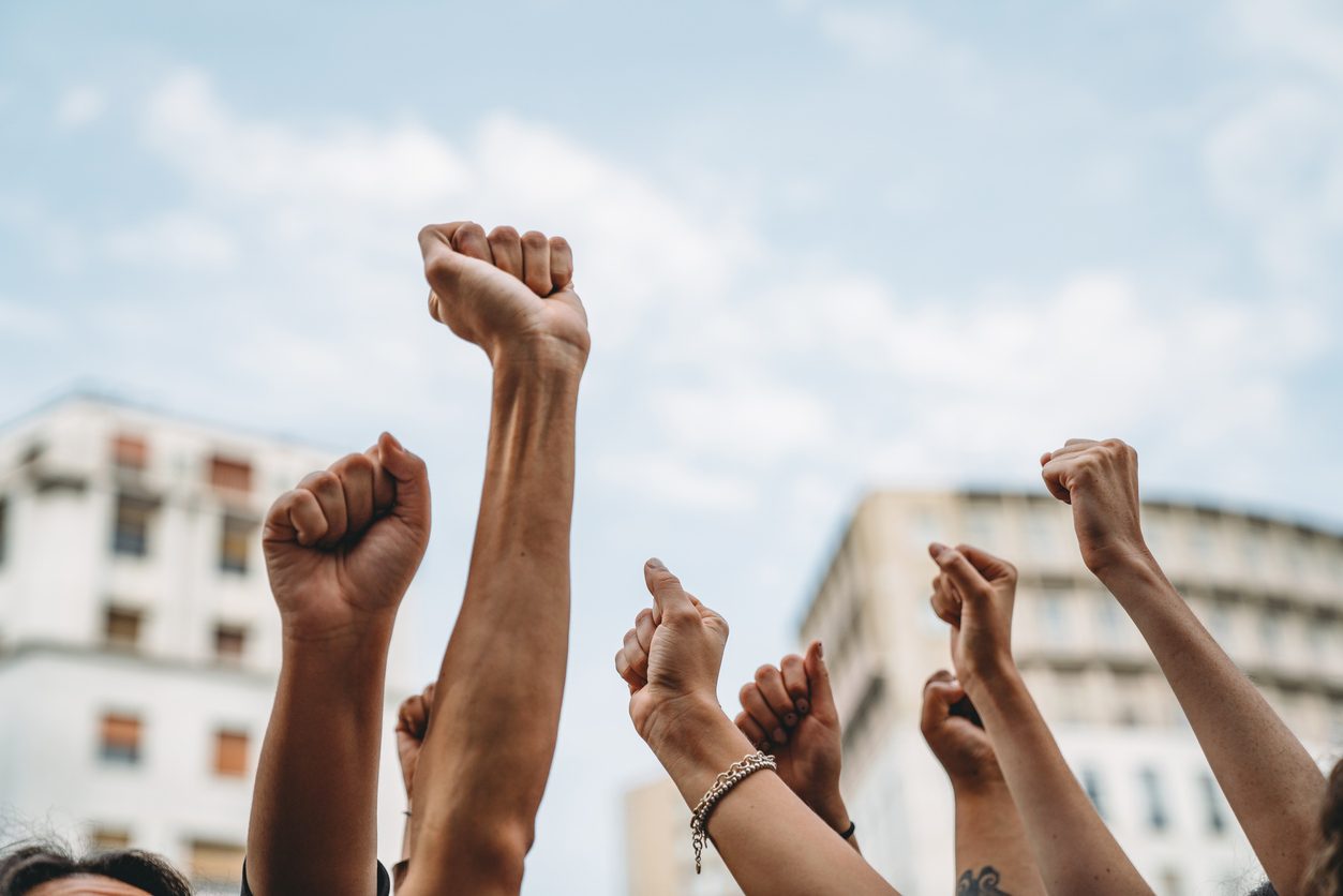 closeup of hands raised as if symbolizing a strike or a union