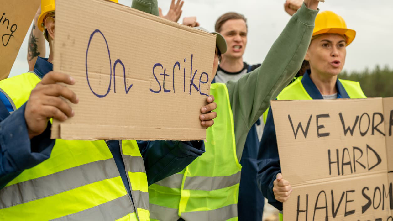 A group of construction workers holding signs that say on strike have resigned.