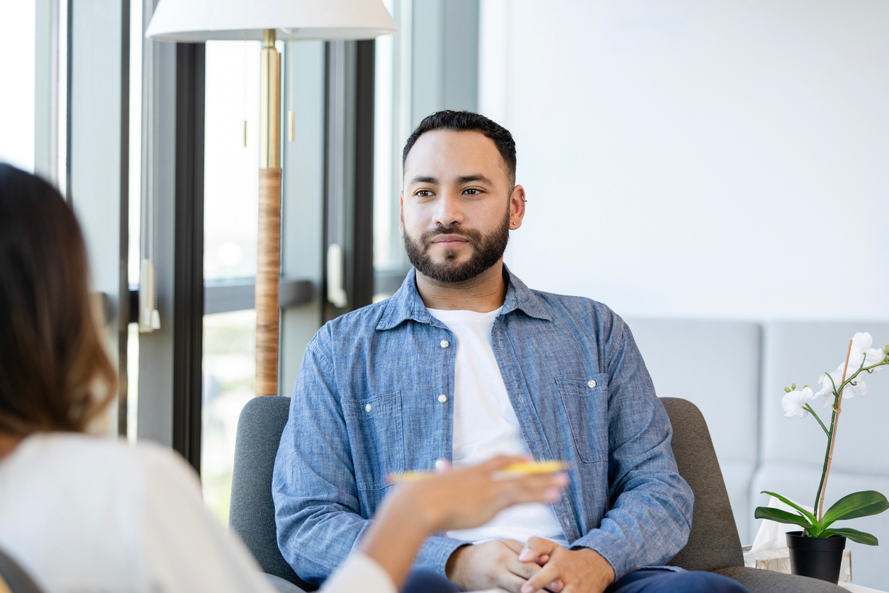 A young man listens as an unrecognizable female counselor gives him advice during a counseling session.