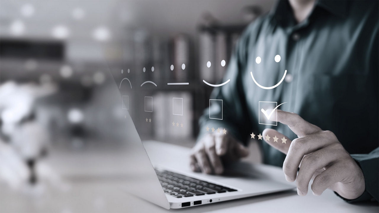 A man is using a laptop with a smiley face on it.