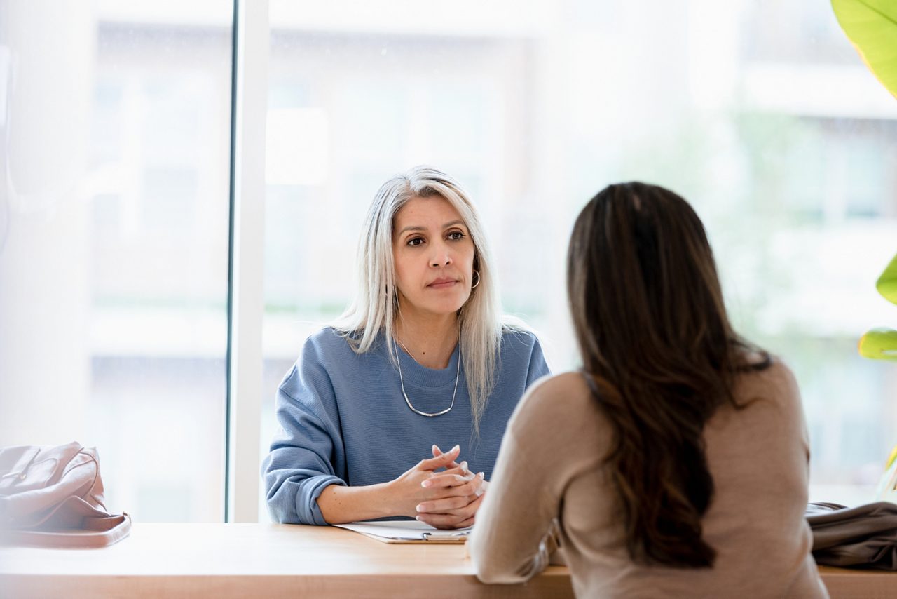 two women talking at desk