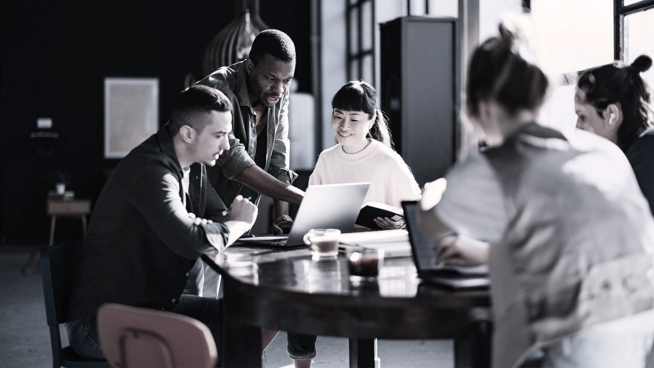 Image of business professionals sitting at a table discussing a project.