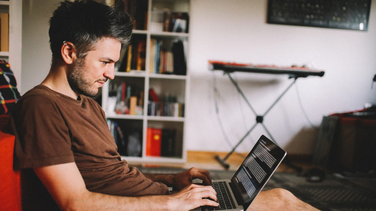 A man sitting on a couch using a laptop.