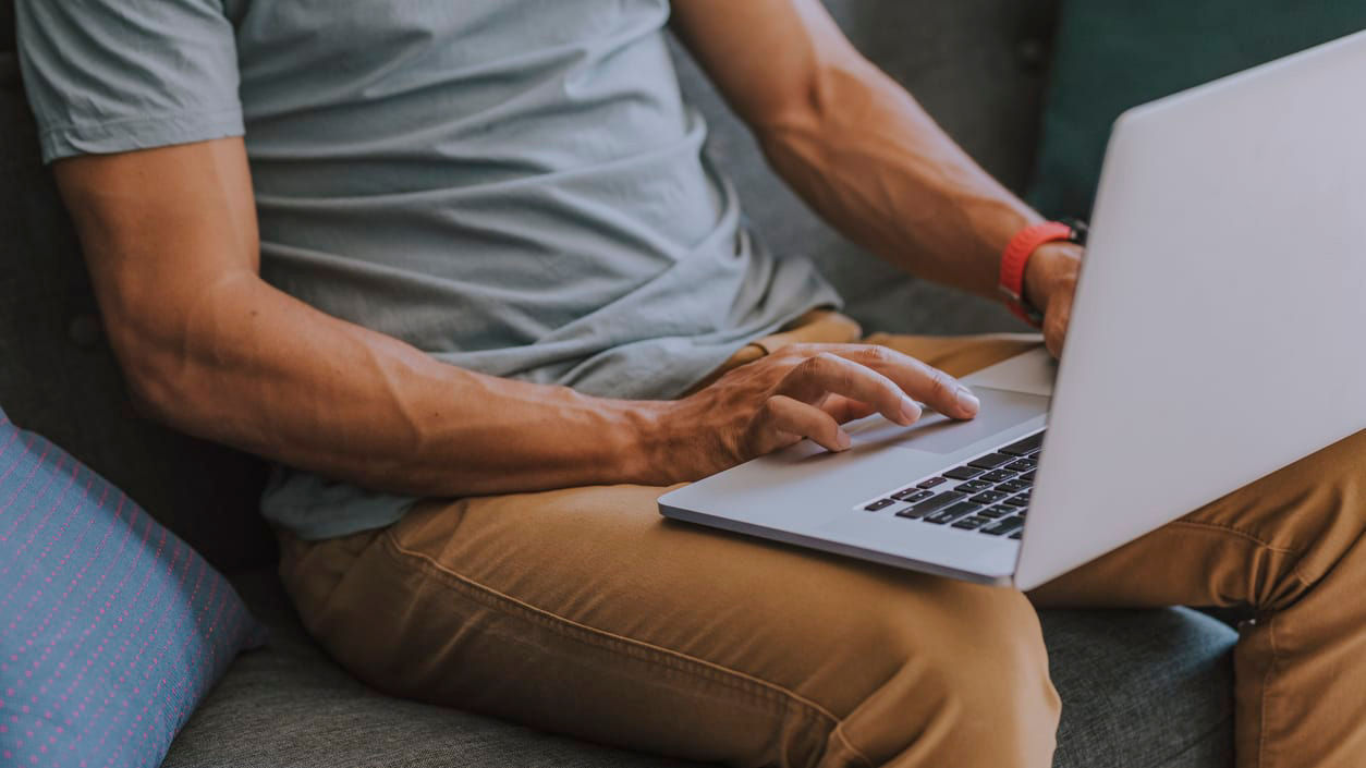 A man sitting on a couch using a laptop.
