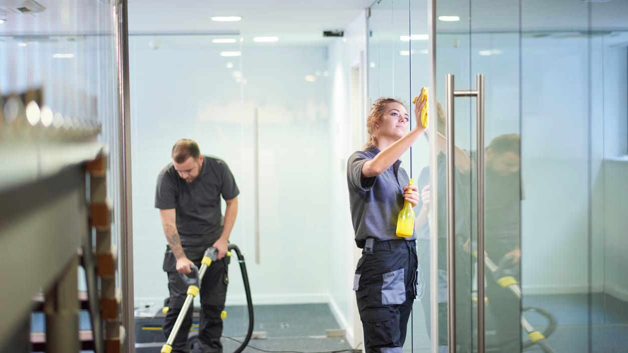 Two men cleaning glass doors in an office.