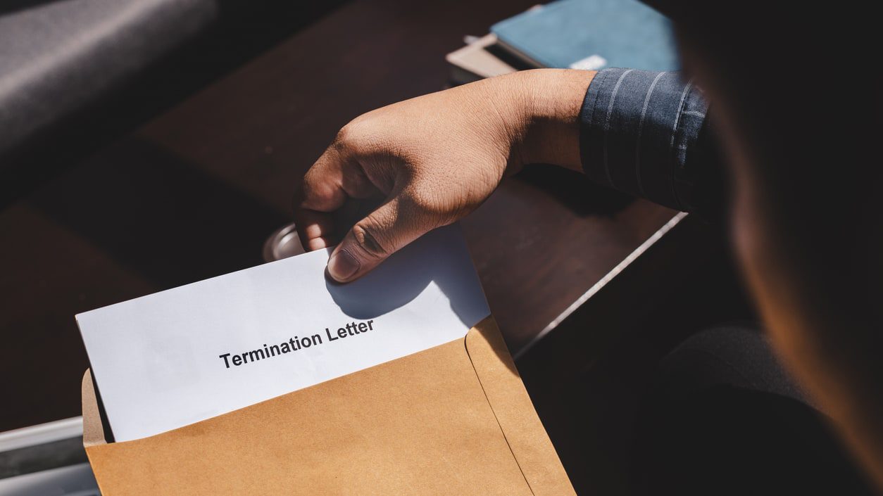 Someone taking a termination letter out of an envelope.