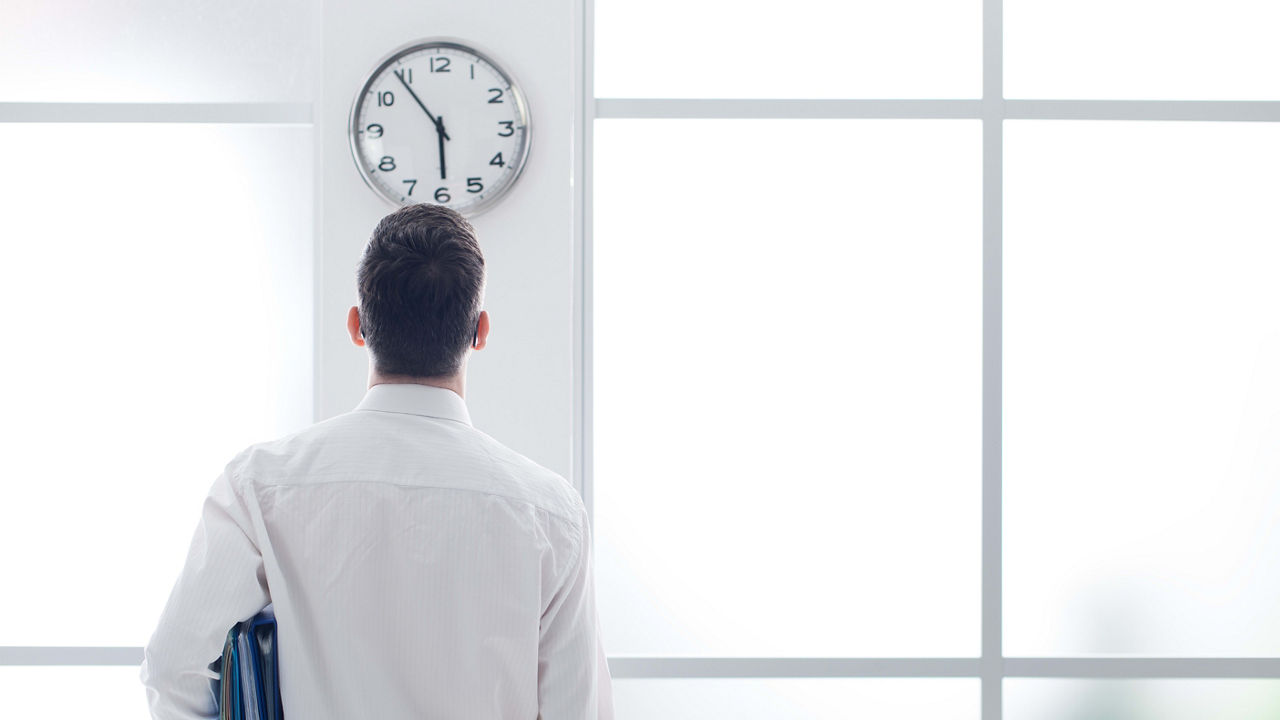 A man looking at a clock in an office.