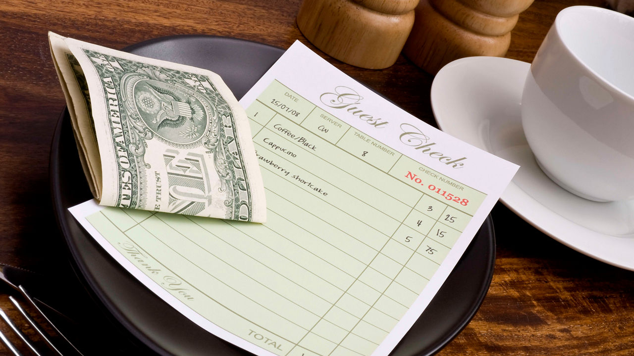 Cash receipt on a plate with a cup and fork.