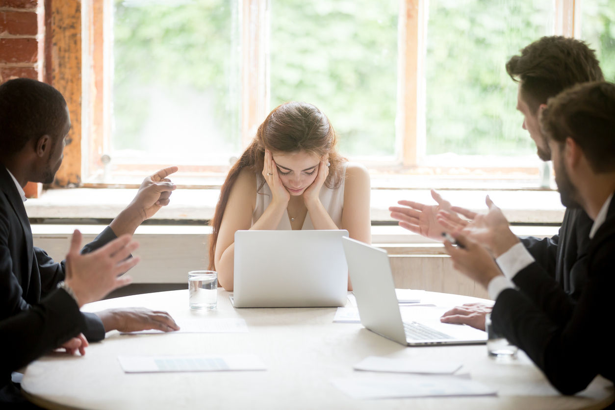 male leaders pointing fingers and upsetting female colleague in a meeting