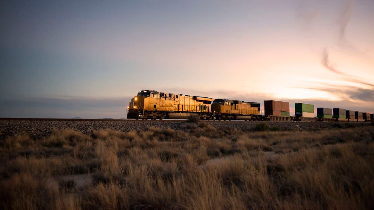 A train traveling through the desert at sunset.
