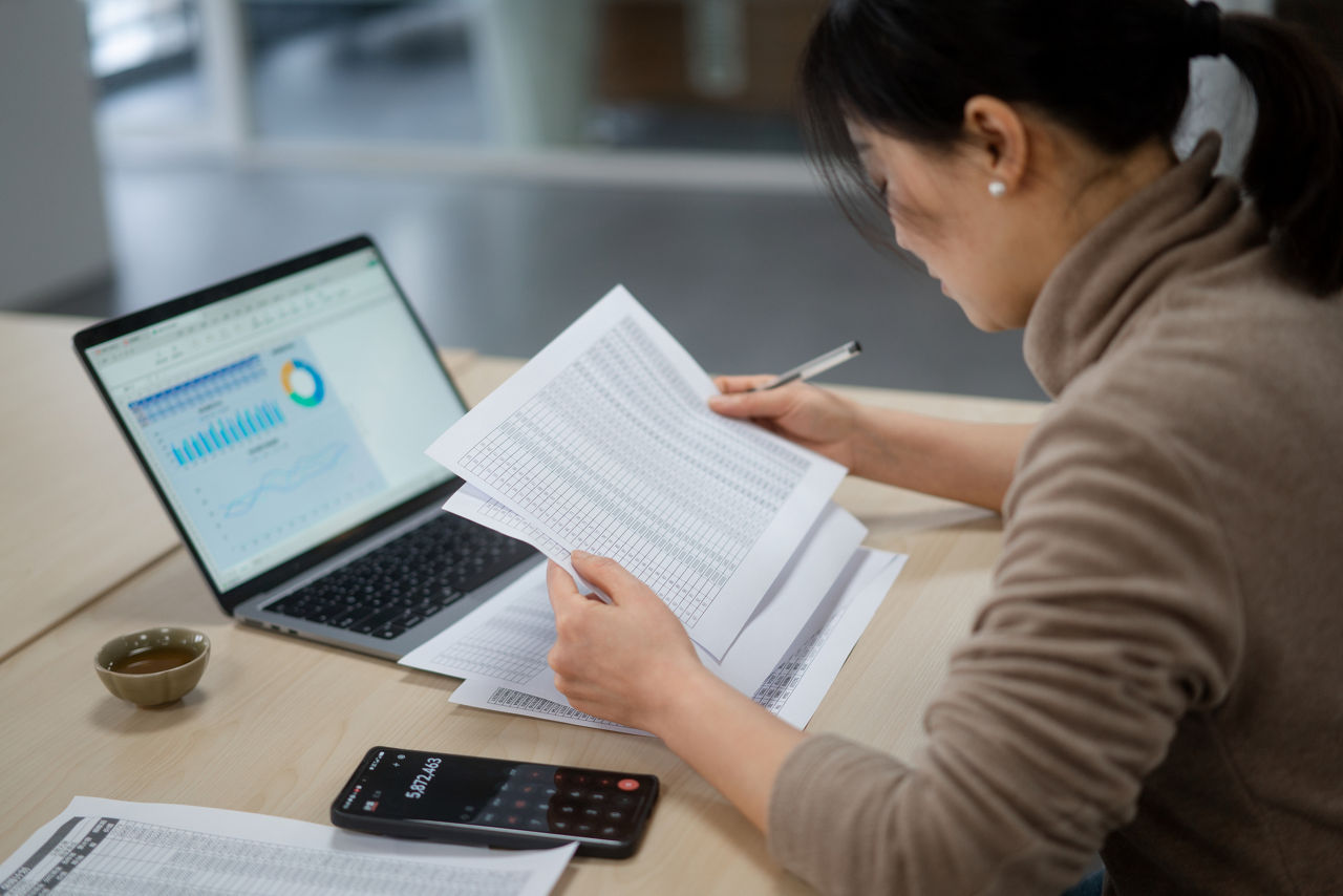 An Asian businesswoman reviews papers from her desk.