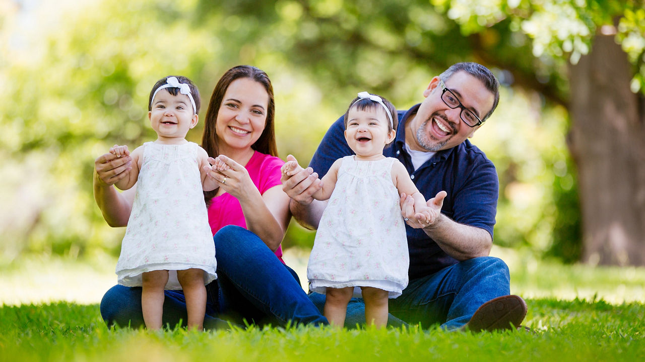 A family sits on the grass with their two daughters.