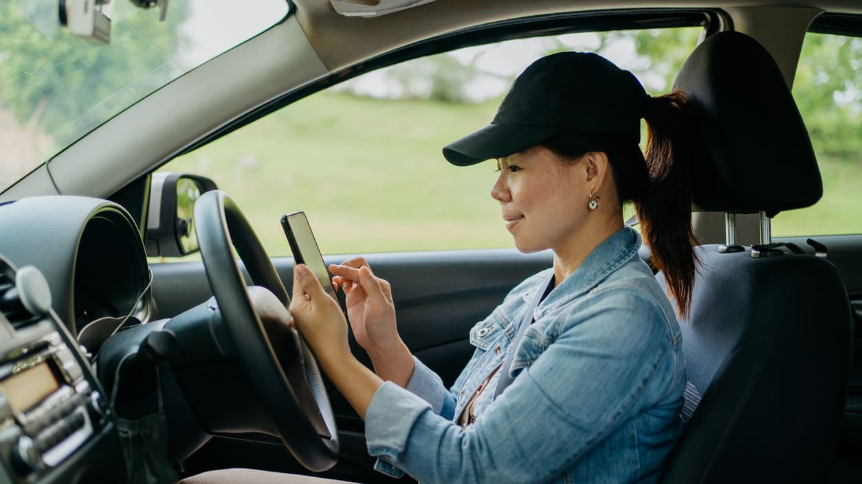 A woman is driving a car while using her cell phone.