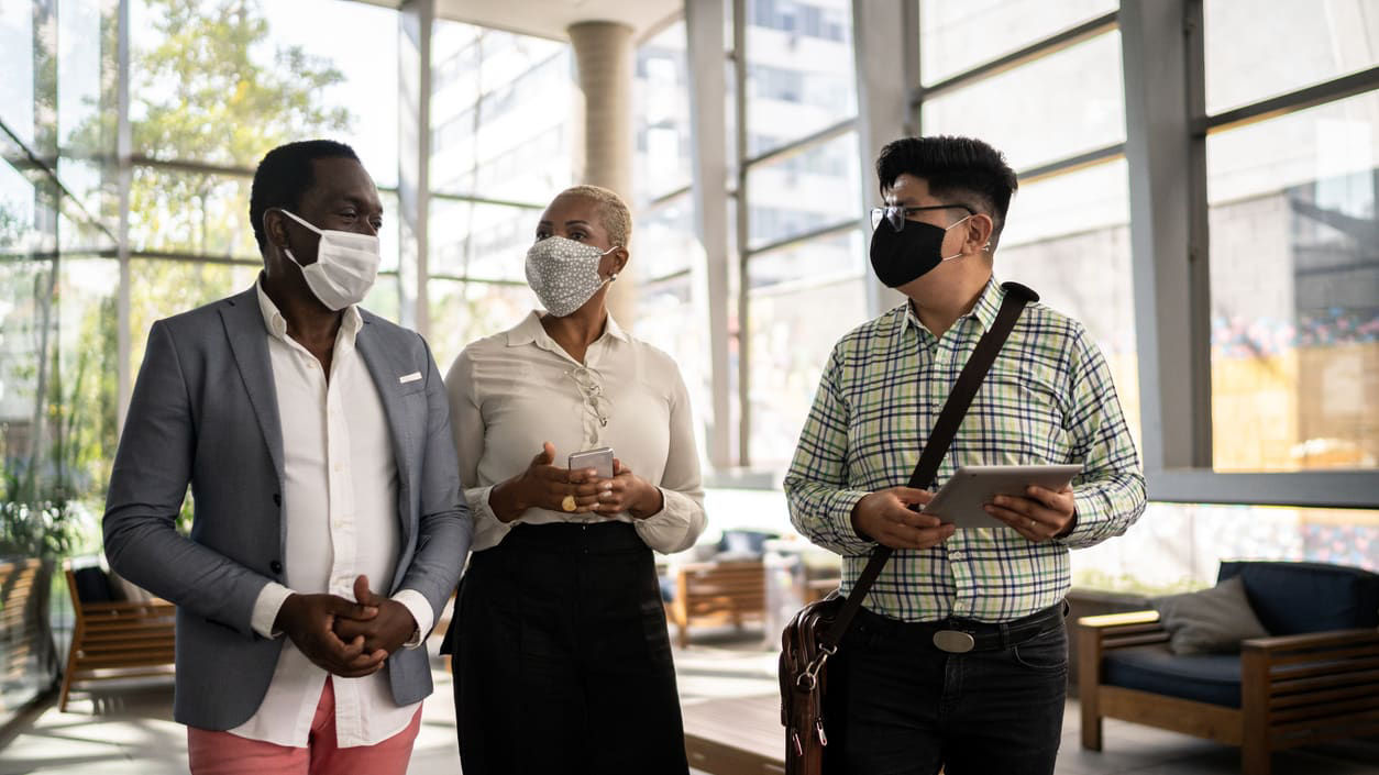 Three people wearing face masks standing in a lobby.