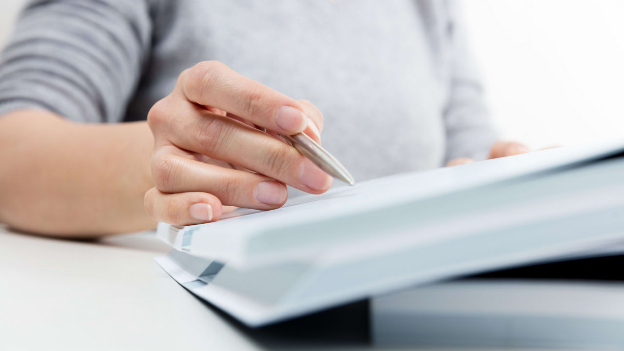 A woman holding a pen and writing in a notebook.