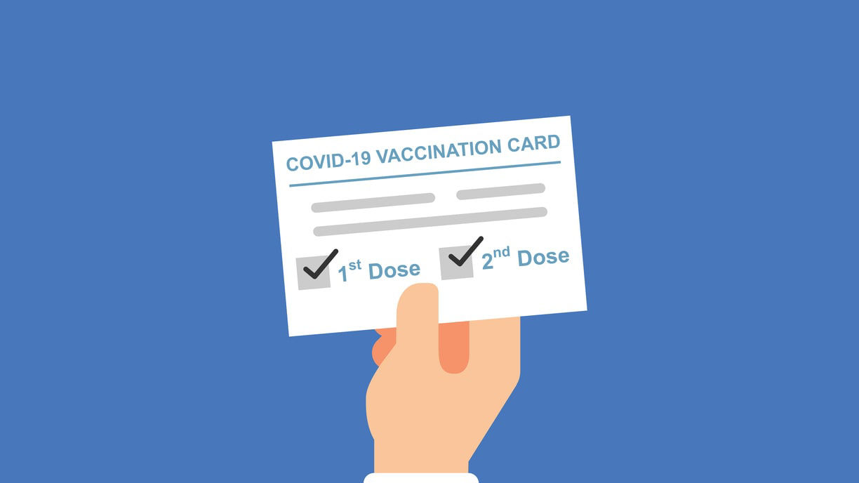 A hand holding up a covid vaccination card.