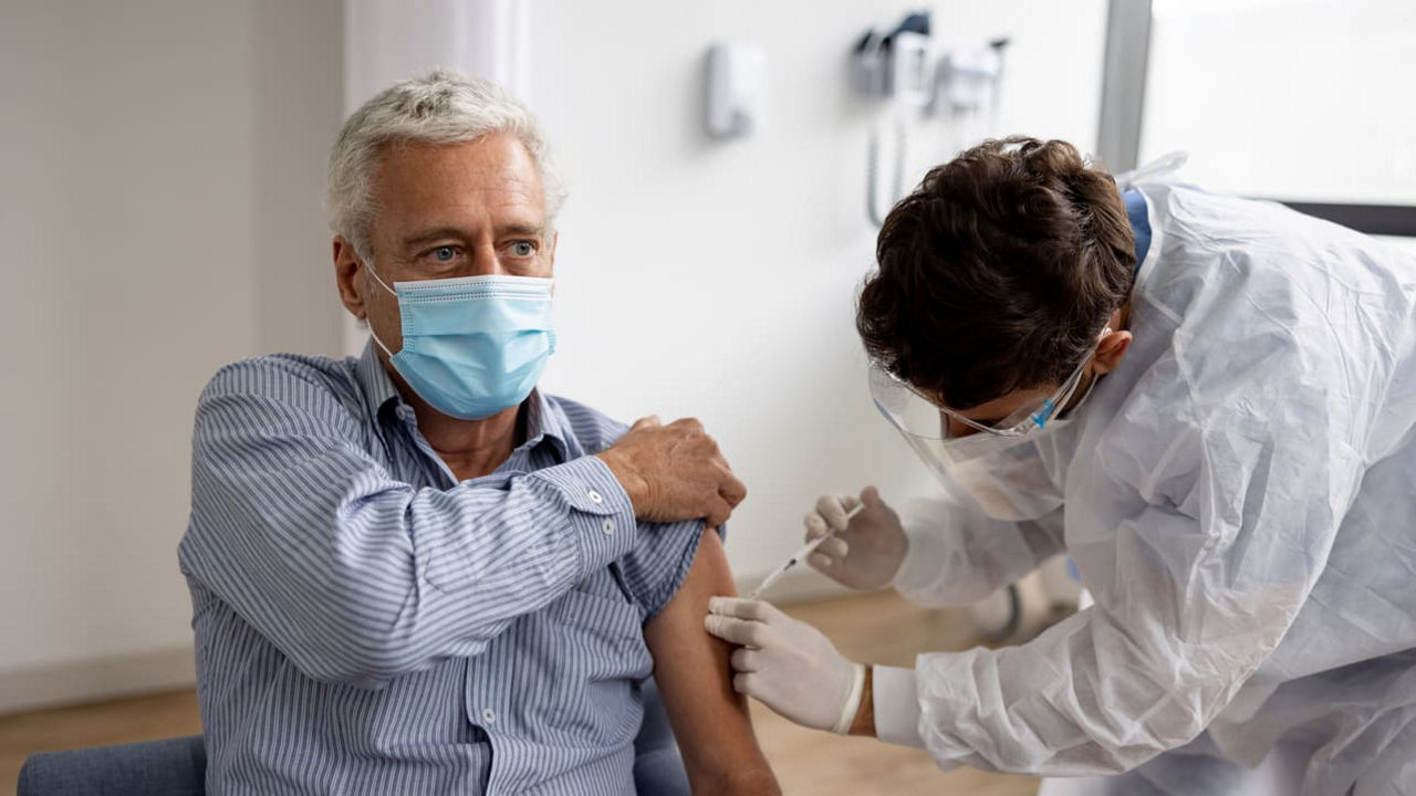 An older man getting a vaccine in a hospital.