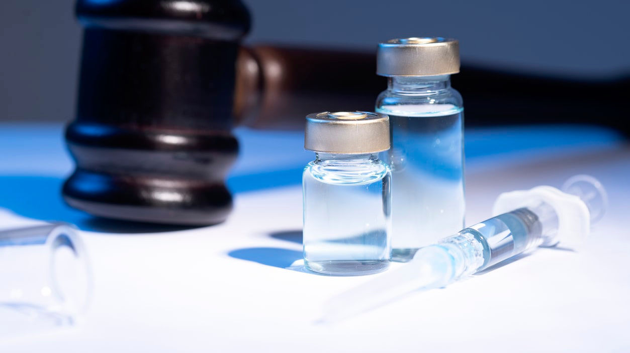 Two syringes and a gavel on a table.