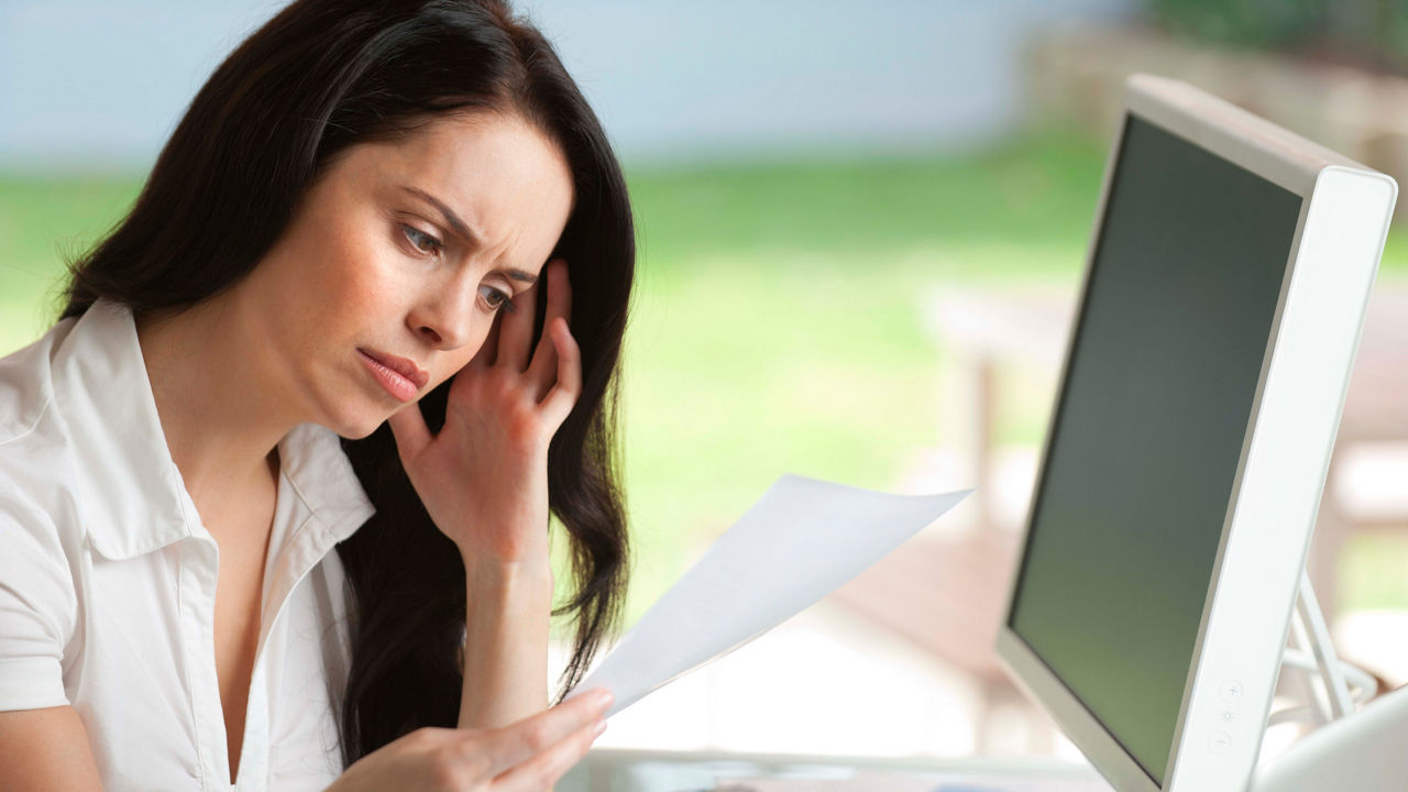A woman is sitting at a desk with papers in front of her.