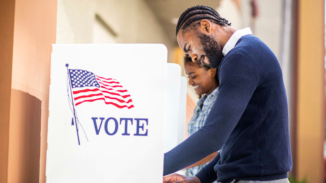 A man and woman voting in a voting booth.