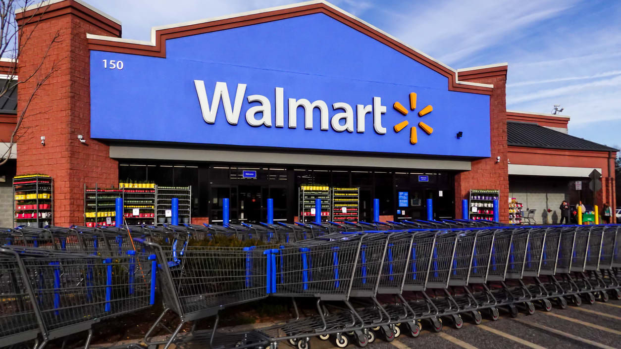 A photo of a walmart store with shopping carts parked outside.