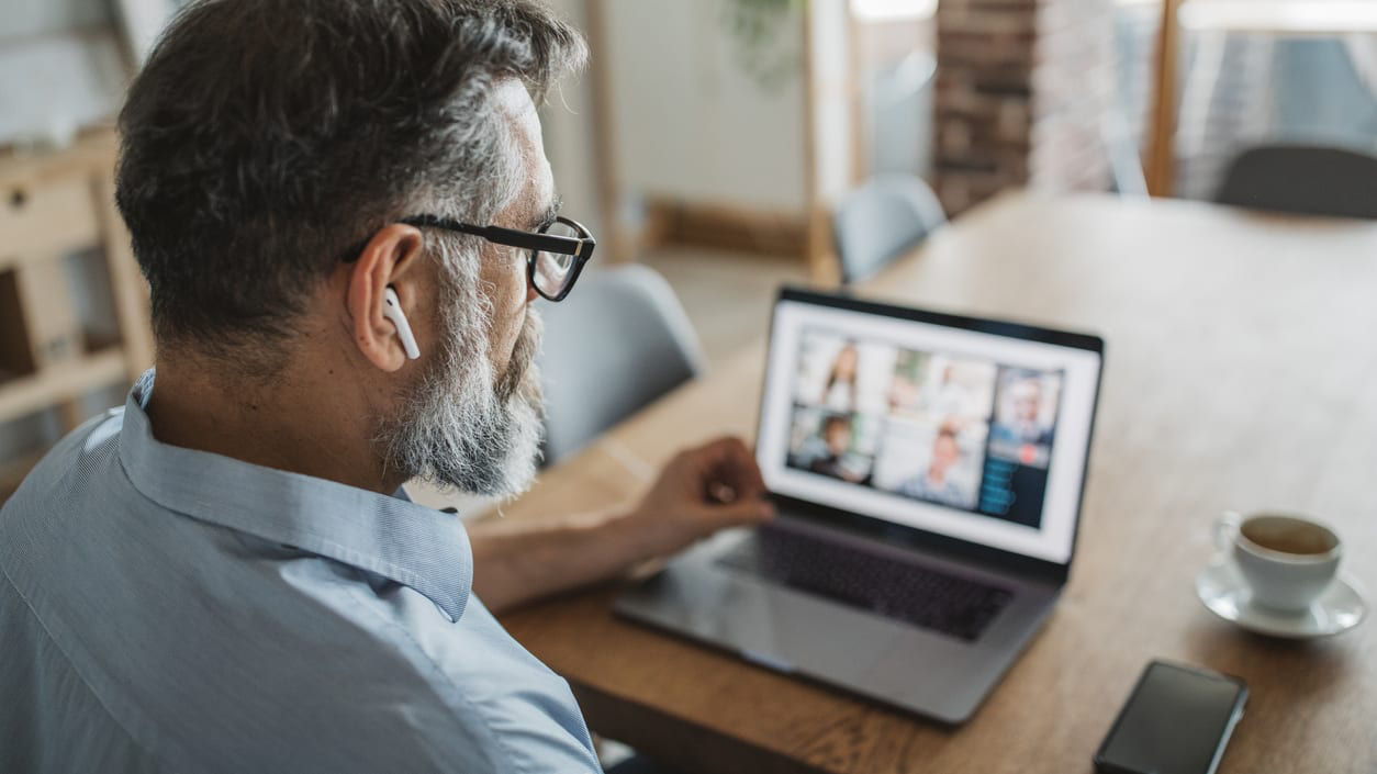 A man sitting at a table with a laptop in front of him.